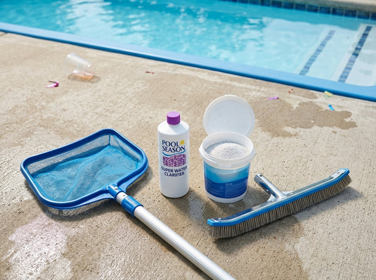 Pool cleanup tools and chemicals laid out on a poolside deck